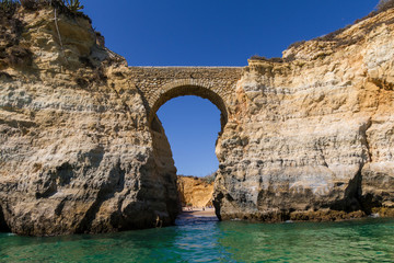Fototapeta na wymiar Entrada a la playa desde el mar con un arco de piedra natural en Punta Piedade, Portugal