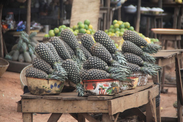 stosy świeżych ananasów ułożonych na straganie przy drodze w afrykańskim miasteczku