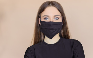 Girl in a black medical mask on a beige one-ton background.