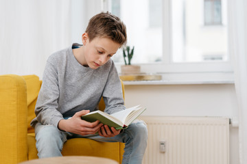 Young teenage boy sitting reading a book - Powered by Adobe