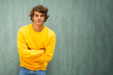 male fashion model in yellow sweater against green background