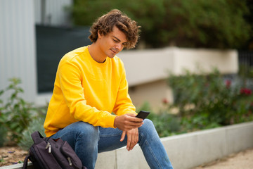 Obraz premium young man sitting outside looking at mobile phone