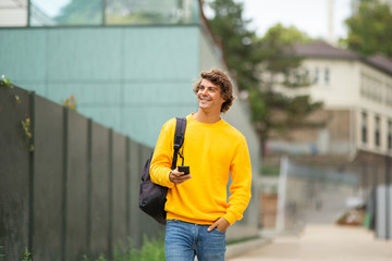 attractive young man walking with bag and mobile phone