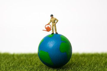 miniature farmer standing on globe with white background © nerosu