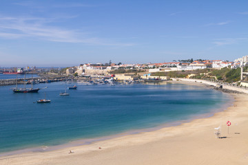 Gran playa con un pueblo marinero al fondo y un puerto pesquero al final de la playa.