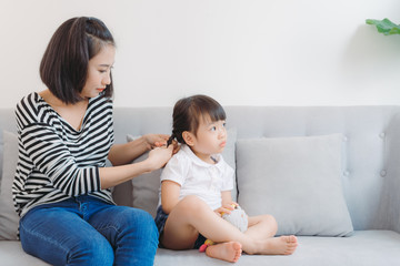 Mother doing styling hair braids for her little girl child.