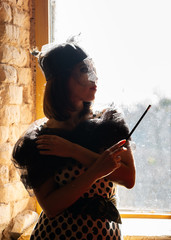 Portrait near window of woman in vintage style with veil and mouthpiece