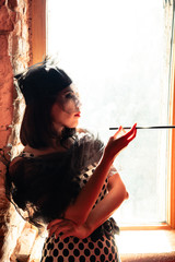 Retro image of beautiful woman near window with mouthpiece
