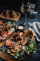 Assorted seafood on a large plate with a bottle of wine, table setting for dinner. Traditional Italian food. Seafood Wine Concept.