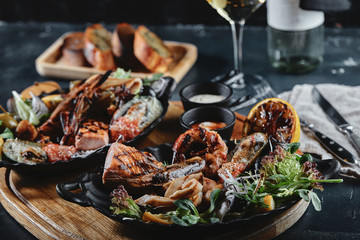Assorted seafood on a large plate with a bottle of wine, table setting for dinner. Traditional Italian food. Seafood Wine Concept.