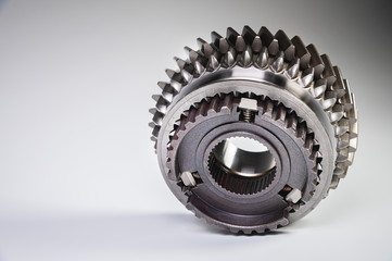 New parts on a gray background. Gears of gear shifting torque transmission. Conceptually mechanical background. Shiny gear box gear teeth