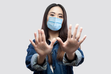 Portrait of scared beautiful asian young woman with surgical medical mask in blue denim jacket...