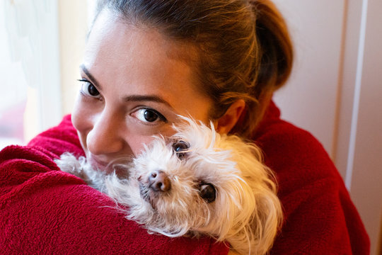 ritratto di una ragazza chiara con gli occhi grandi e scuri vestita di rosso vicina al suo cane di razza maltese