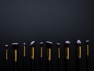 
Makeup brushes on black wood background.