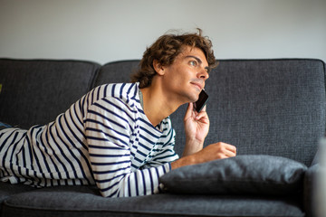 Fototapeta premium young man relaxing on couch talking with cellphone
