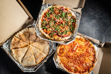 Pizzas in a cardboard box against a dark background. Space for text