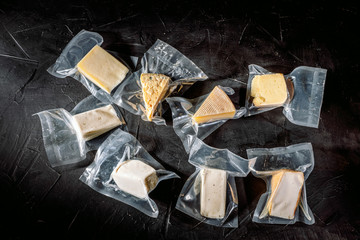 Different kinds of cheese in vacuum package on a dark background