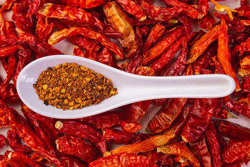 Crushed red pepper, cayenne pepper, dried chile flakes on a white wooden base. Texture. Very hot.