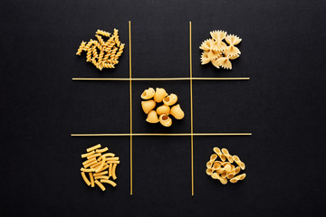 Tic tac toe game with pasta on black background