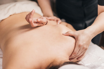 Obraz na płótnie Canvas Hands of a masseuse on a female back during work - treatment of diseases of the back and spine - elimination of back muscle clamps