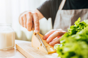 A man slices thin slices of cheese for sandwiches - a beautiful cozy home look