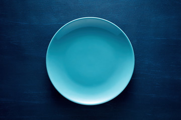 One empty blue round plate or dish on blue background