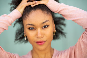 Close up beautiful young african american woman staring with hands in hair