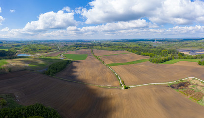 Fototapeta na wymiar aerial view of fields and forests in spring with beautiful clouds