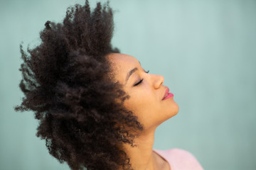 side portrait beautiful young black woman with afro hair by green background