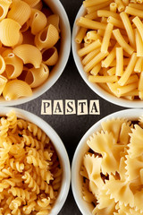 Template for pasta recipe with various raw pasta in white bowls