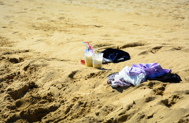 Two cocktails and discarded clothes before swimming in the sea on the beach