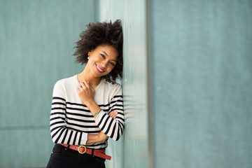 Fototapeta premium smiling young african american woman leaning against wall