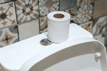 Roll of paper on toilet tank in bathroom, closeup