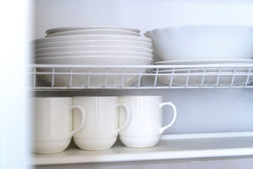 White porcelain dishes dried on metal dish rack.