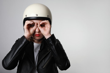 Young biker woman doing a hand gesture looking through binoculars. Free space for text.
