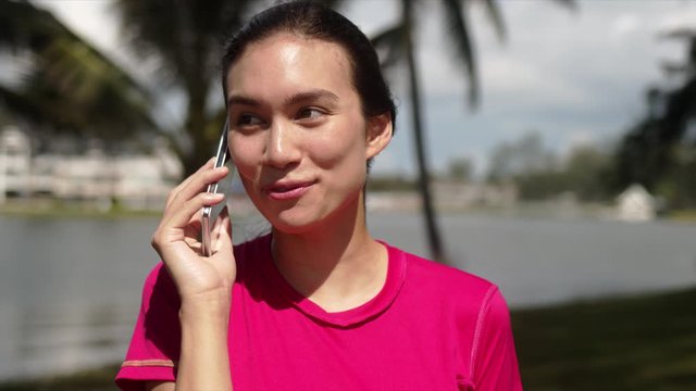 Modern active female in sportswear talking on smartphone and smiling while standing