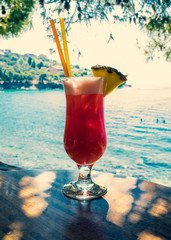 Refreshing orange cocktail on beach table. Island sea and sky background - soft focus.