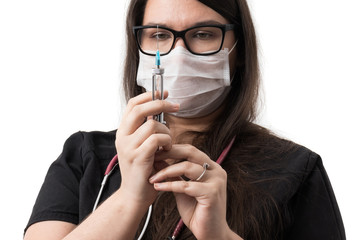 Female doctor in black uniform wearing a mask, holding a retro metal syringe, isolated on white background