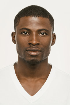 Attractive African american man looking seriously at the camera, Dark-skinned guy in a white t-shirt on a white background looks confident, cut out on white. Toned image