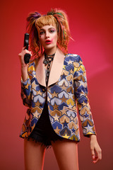Dangerous girl with bright makeup holds a black gun in her hands. Cosplay character from the movie 