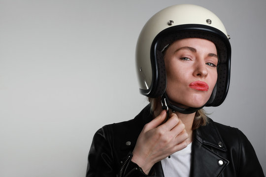 Headshot of happy caucasian woman put retro white helmet on before riding a motorbike. Free space for text.