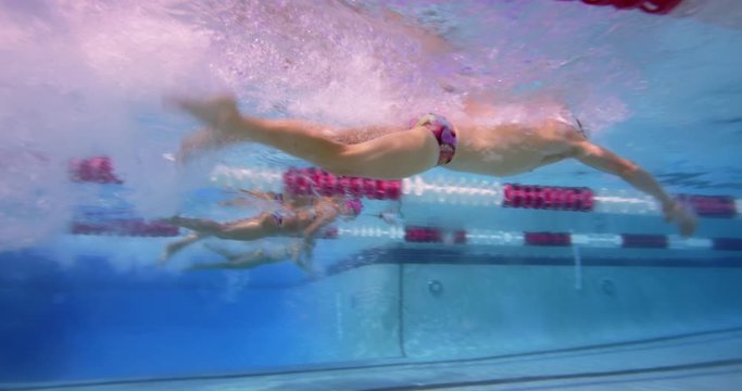 Three swimmers diving in pool underwater