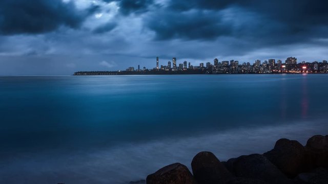 4K Zooming In video of Blue thunderstorm clouds over the city skyline on a stormy monsoon night taken from Marine Drive a popular tourist destination, Mumbai, Maharashtra, India.