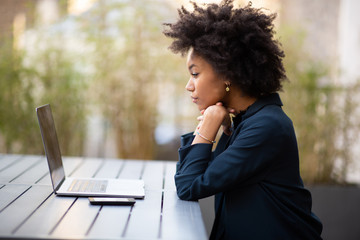 Side of young african american business woman sitting with laptop computer