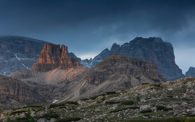 Mountain landscape in the European Dolomite Alps underneath the Three Peaks with alpenglow during sunset, heavy clouds in the sky, South Tyrol Italy.