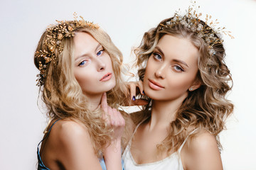 Two blue-eyed girls with hair jewelry. a pair of Young women in a hoop with stones and pearls. The concept of a wedding hairstyle and jewelry