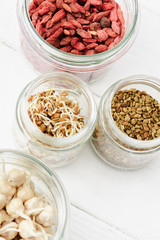 top view of goji berries and sprouts in glass jars on white wooden surface