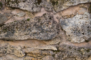 Texture of the stone foot of a mountain, rock or cliff of gray color interspersed with moss