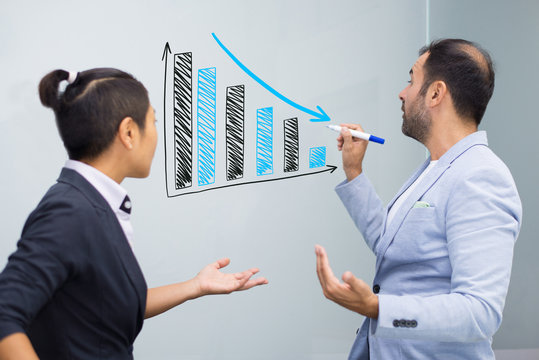 Confident businessman making notes on growing down graphics. Male teacher editing notes of his student with marker. Education or marketing discussion concept - Powered by Adobe