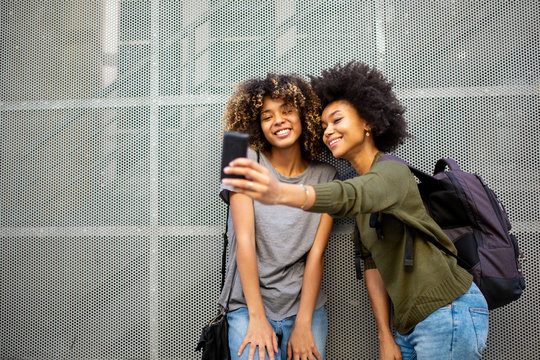 two young african american friends taking selfie with cellphone